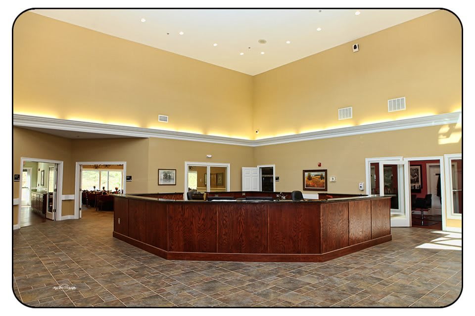 A spacious lobby area featuring a large, wooden reception desk and modern lighting.