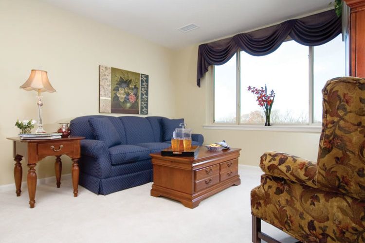 A cozy living room with a blue sofa, wooden coffee table, and artwork on the wall.