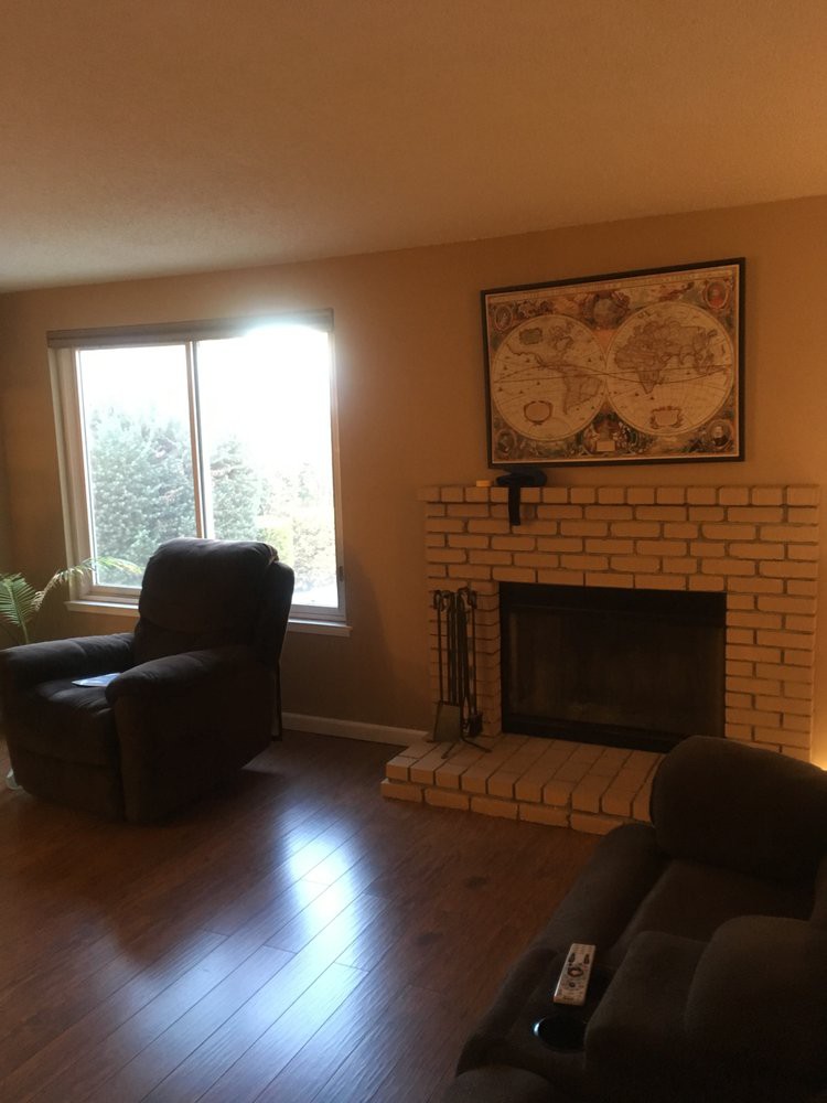 A cozy living room with a fireplace, armchair, and map artwork on the wall.