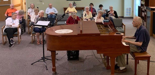 A group of people attending a musical performance featuring a grand piano.
