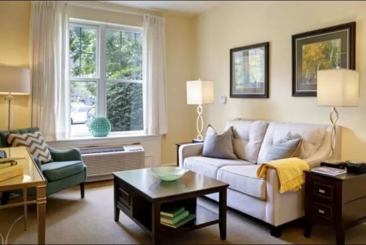 A cozy living room with a sofa, armchair, and coffee table near a large window.