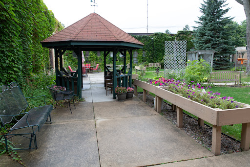 A serene garden featuring a gazebo, benches, and vibrant flowers along the pathway.
