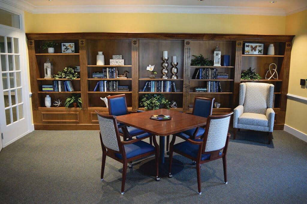 A cozy library space with a wooden table and chairs surrounded by bookshelves.