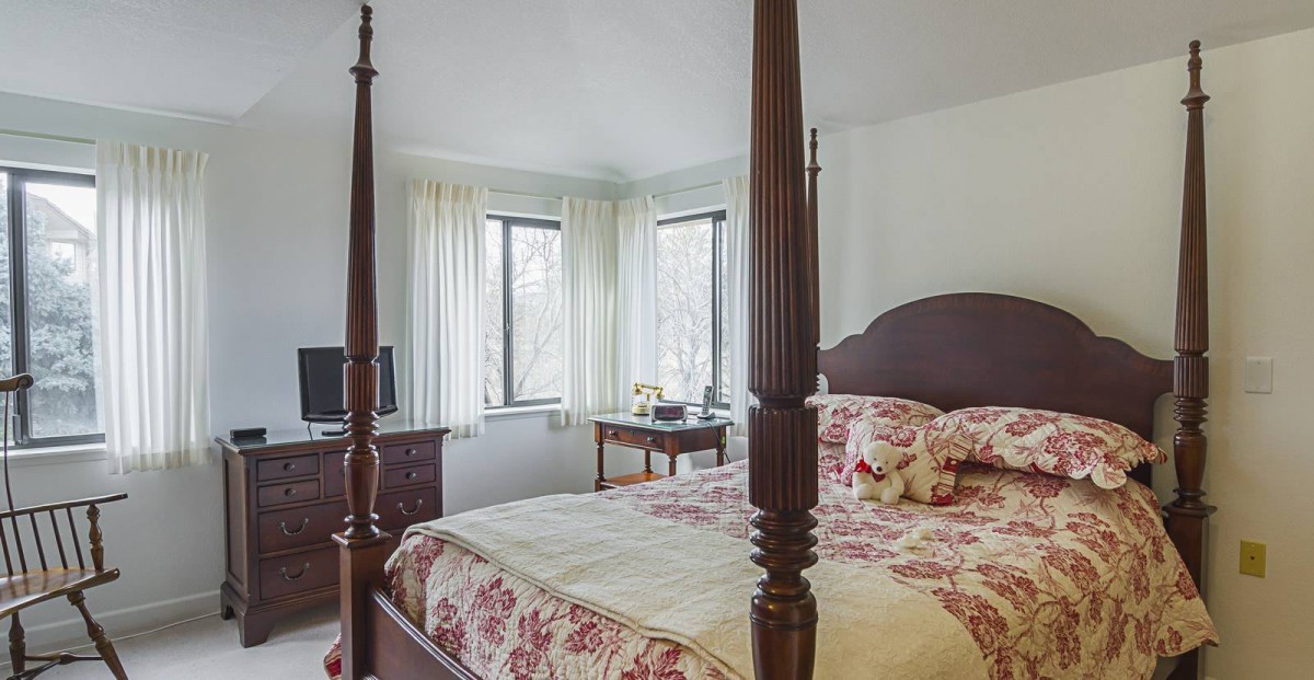 A cozy bedroom featuring a four-poster bed with floral bedding and classic decor.
