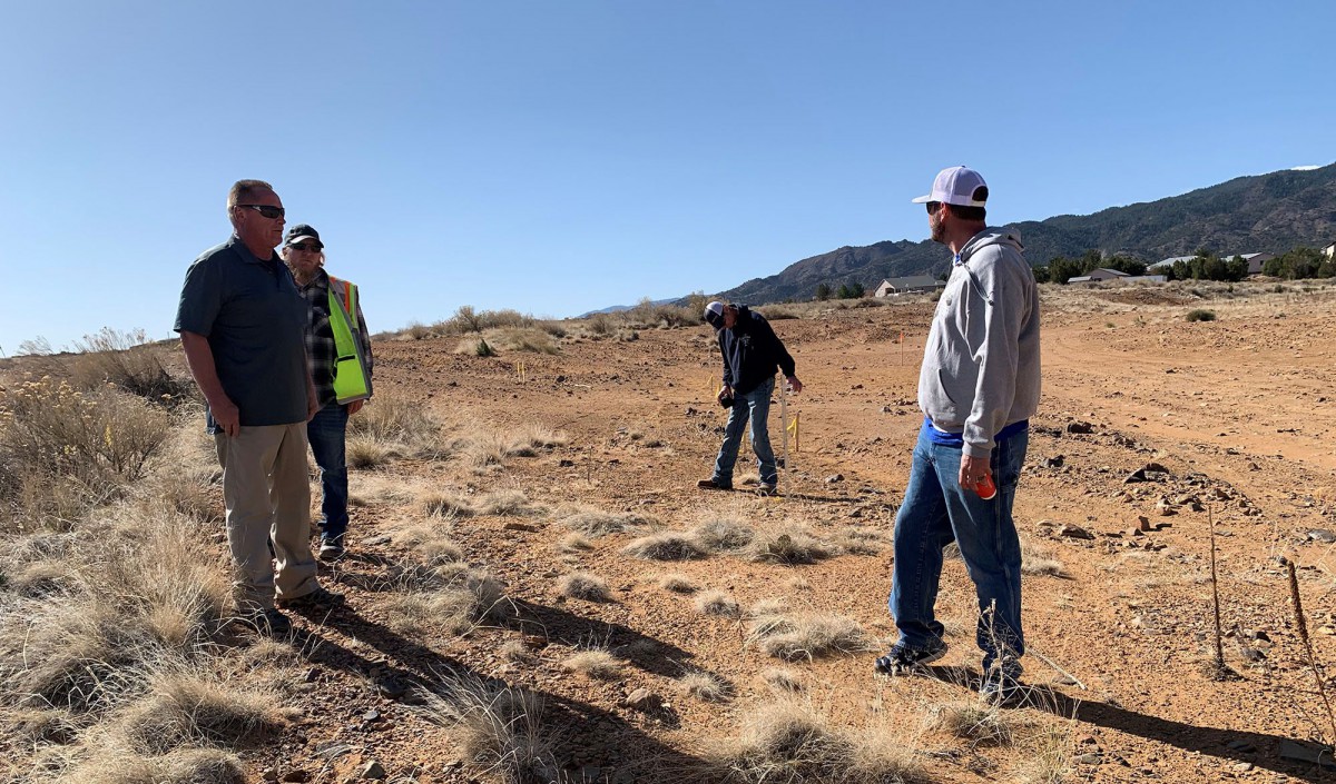 A group of people conducting fieldwork in a desert landscape under clear skies.