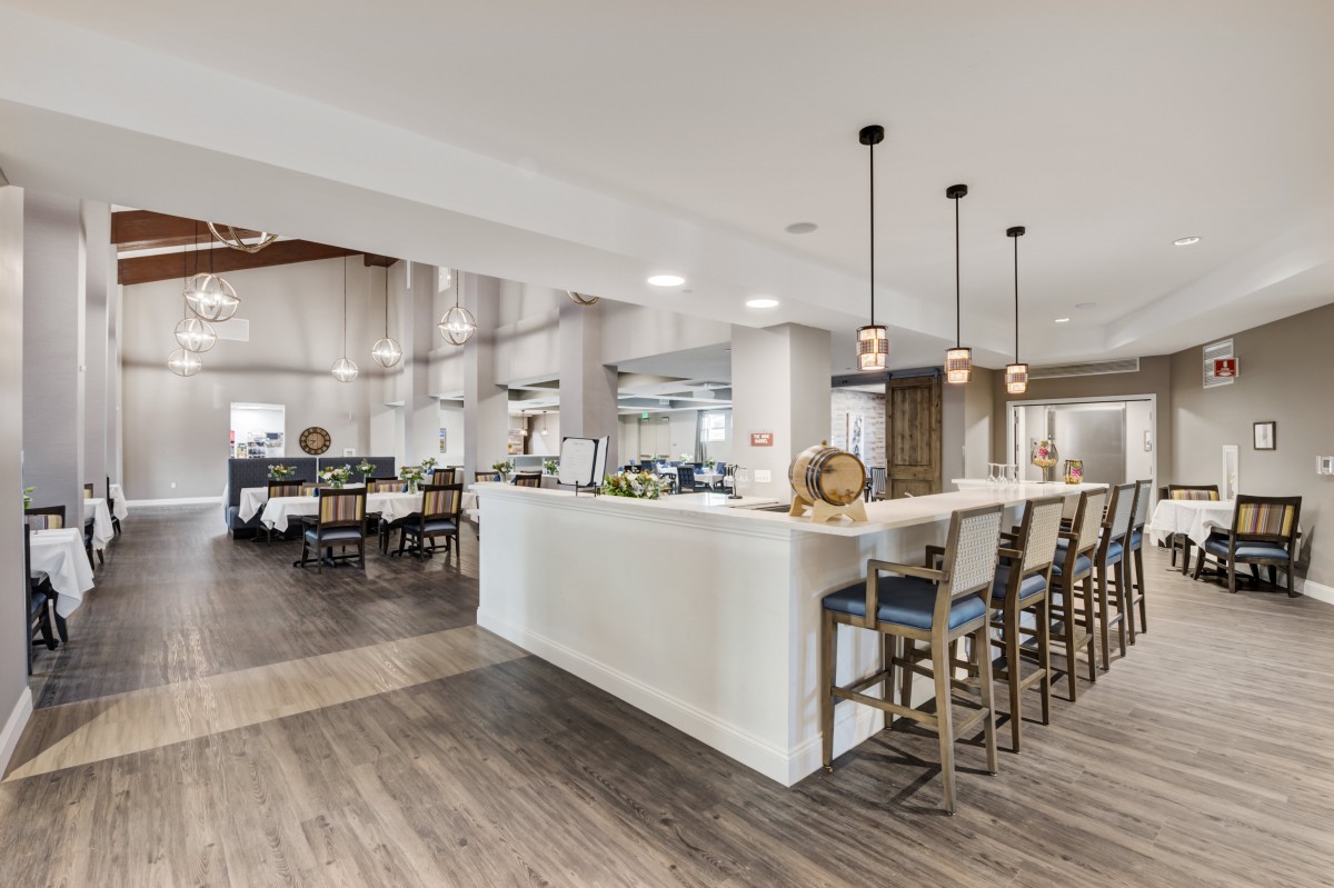 A modern kitchen with a bar counter and pendant lighting, featuring an open layout and wood flooring.