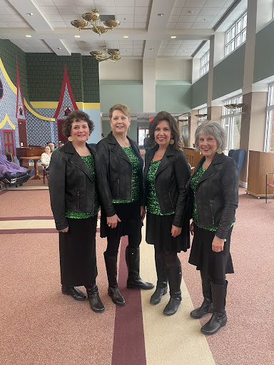 A quartet of women performers dressed in coordinated outfits, ready for a musical presentation.