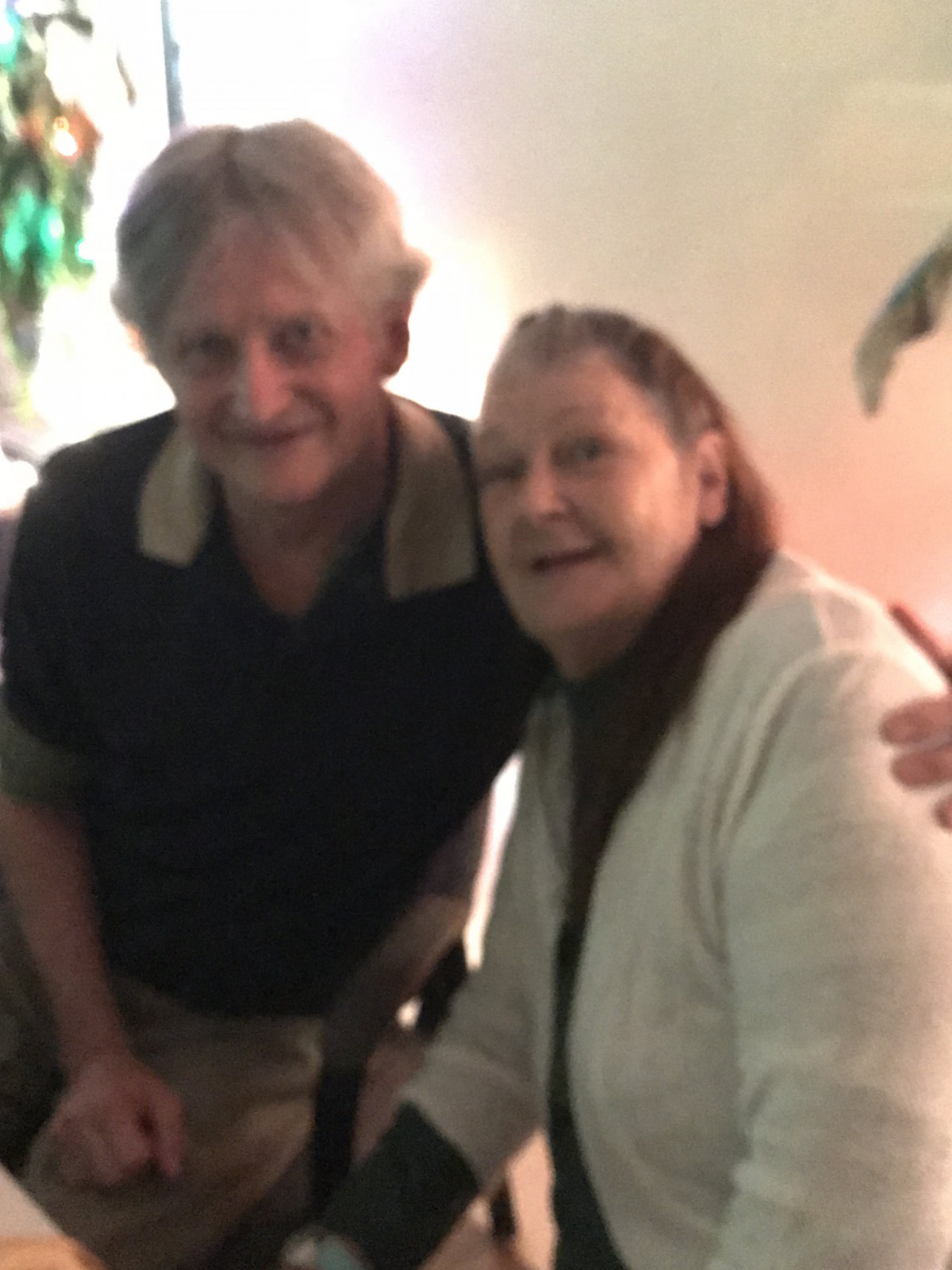 Two people posing together indoors, smiling at the camera.