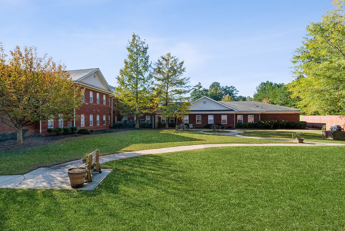 A sunny day at a courtyard with green lawns, benches, and surrounding buildings.