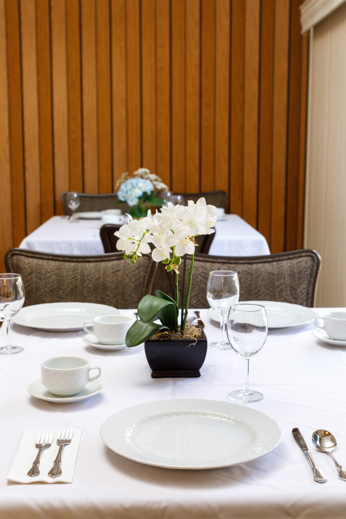 An elegantly set dining table featuring a centerpiece with white orchids.