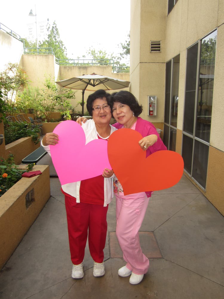Two people holding large colorful hearts, celebrating outdoors.