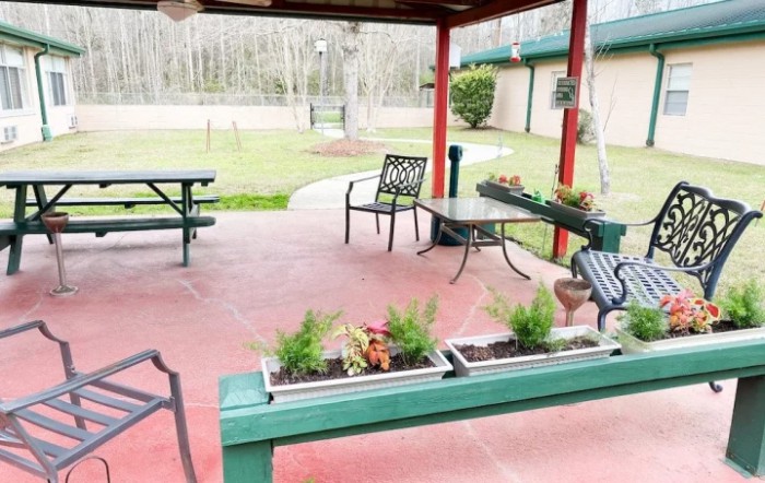 An inviting outdoor patio with seating and planters under a covered area.
