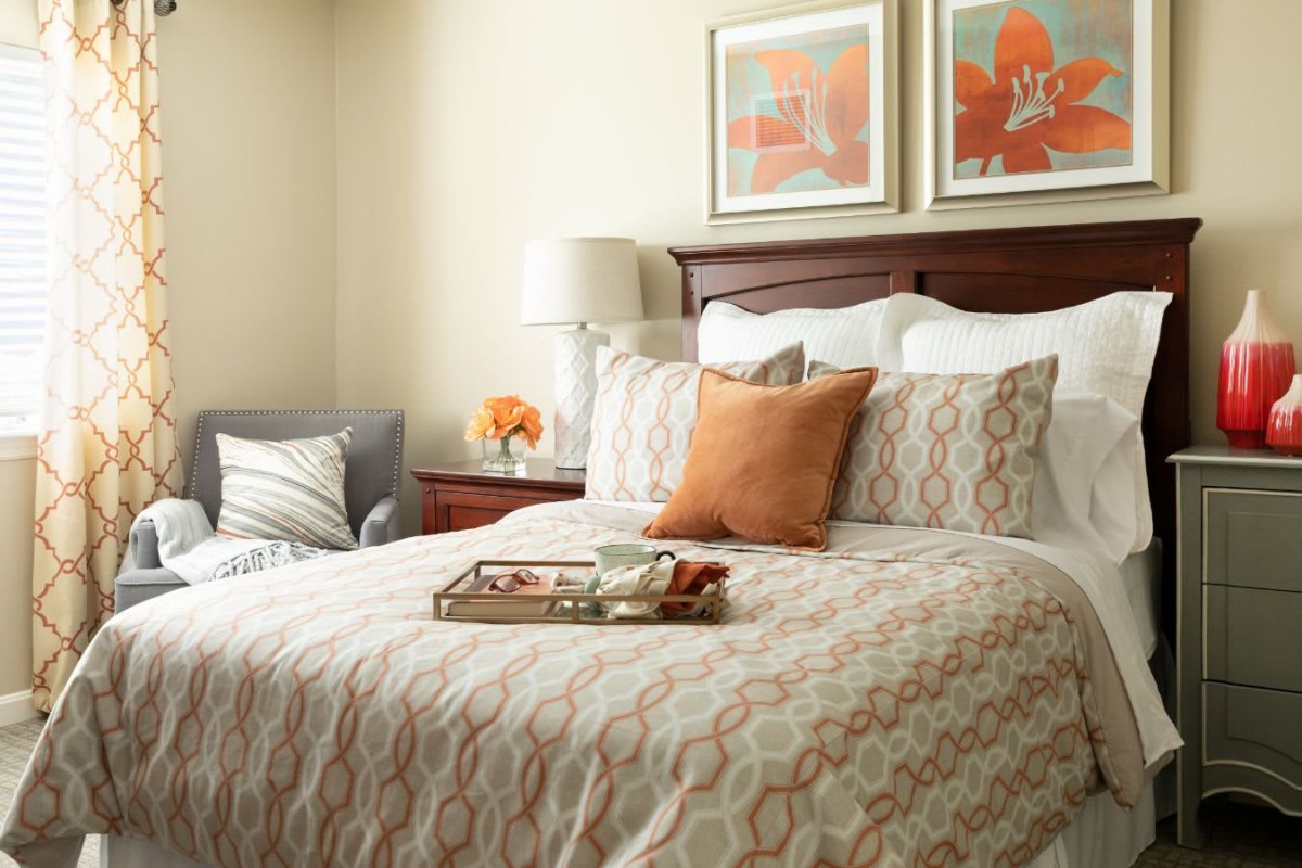 A cozy bedroom with decorative pillows and framed artwork above the bed.