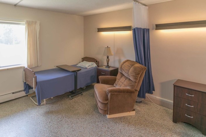 A hospital room with a bed and recliner, separated by a curtain.