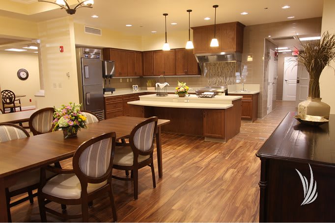 A modern kitchen and dining area with a central island, wood flooring, and elegant lighting.