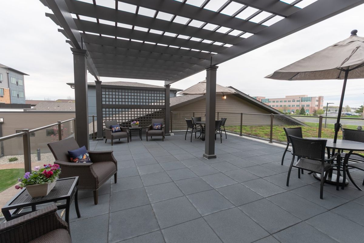 A rooftop patio with a pergola, featuring outdoor seating and tables.