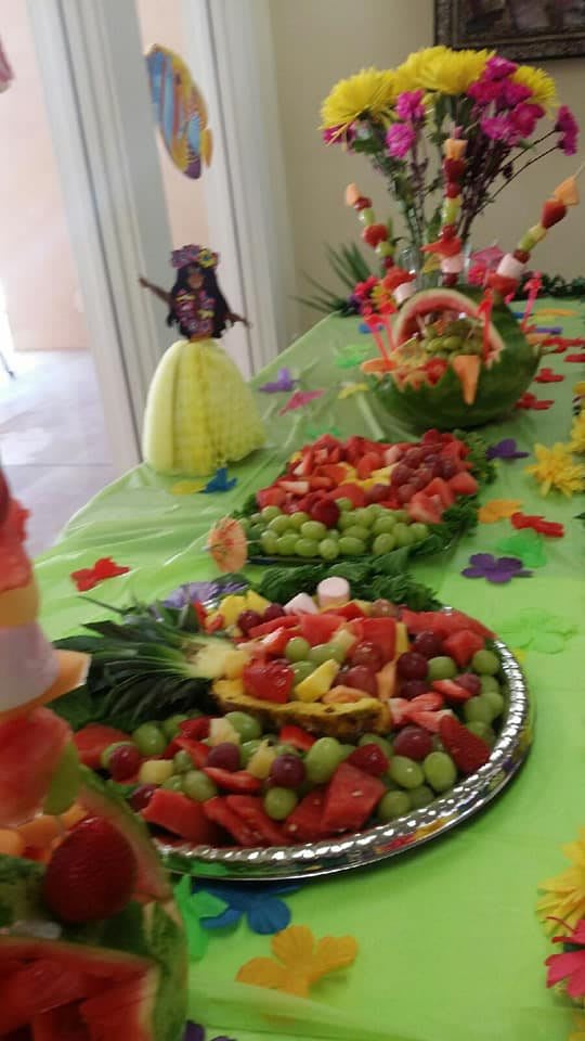 A tropical-themed party spread with colorful fruit platters and decorative elements.