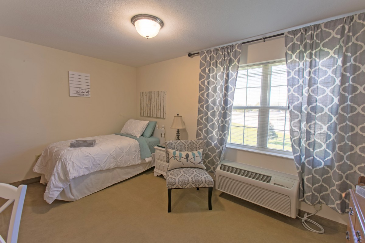 A cozy, well-lit bedroom with a single bed and patterned curtains.