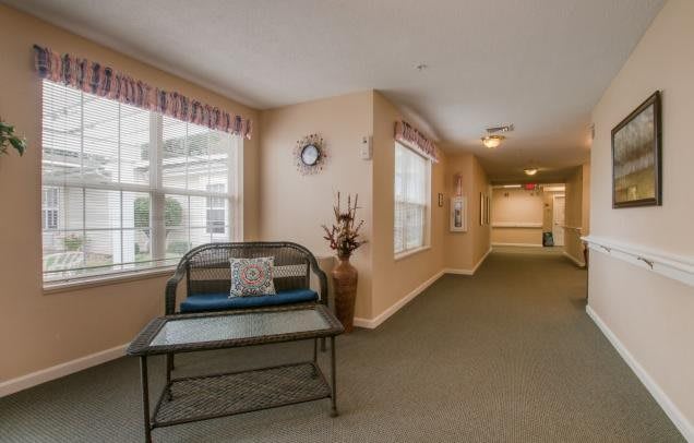 A cozy hallway with a bench and windows, featuring decorative elements and a wall clock.