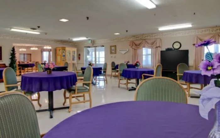 An empty dining area with tables covered in purple tablecloths.