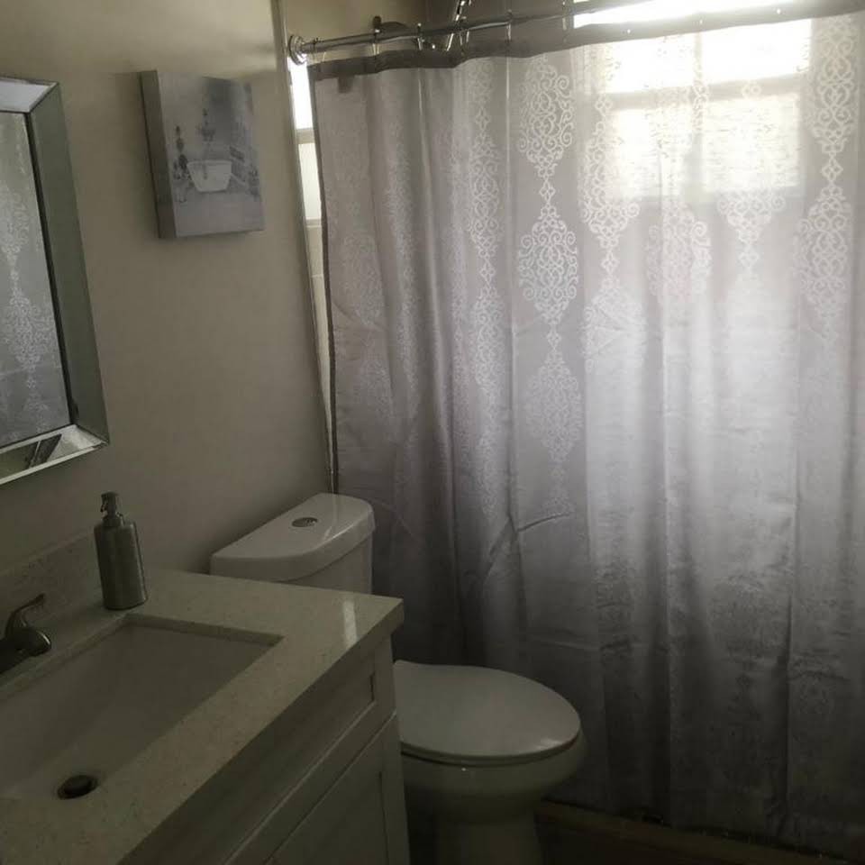 A small bathroom with a sink, toilet, and shower with a curtain.
