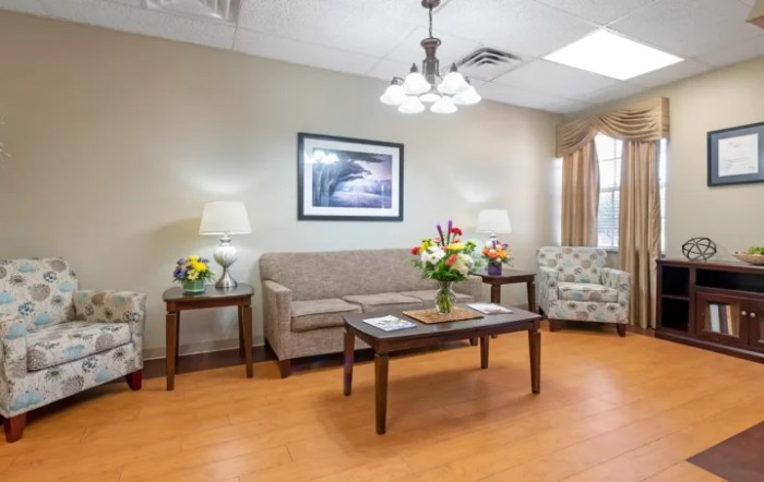A cozy living room with a sofa, armchair, and a coffee table adorned with fresh flowers.