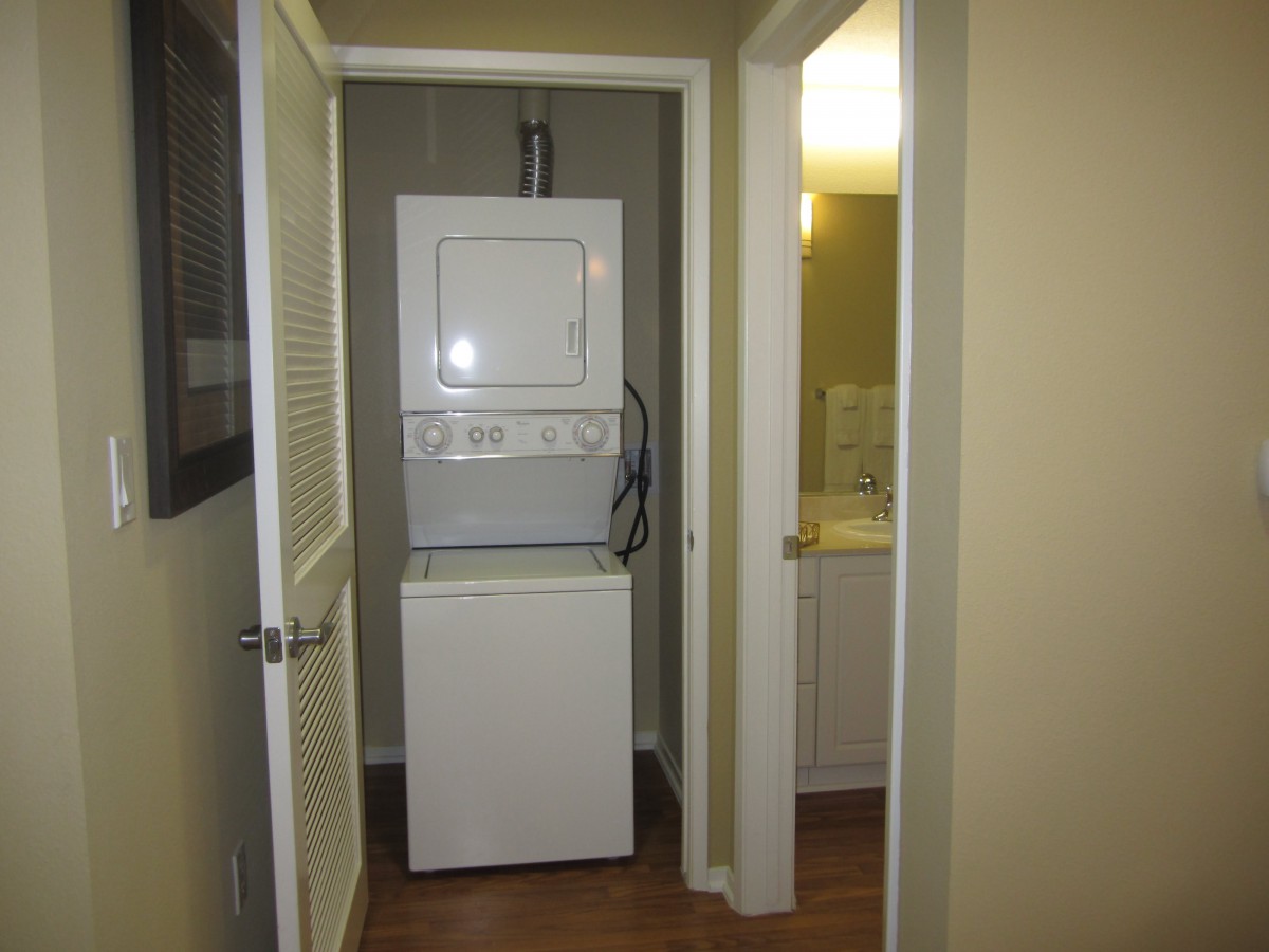 A compact laundry area with a stacked washer and dryer in an apartment hallway.