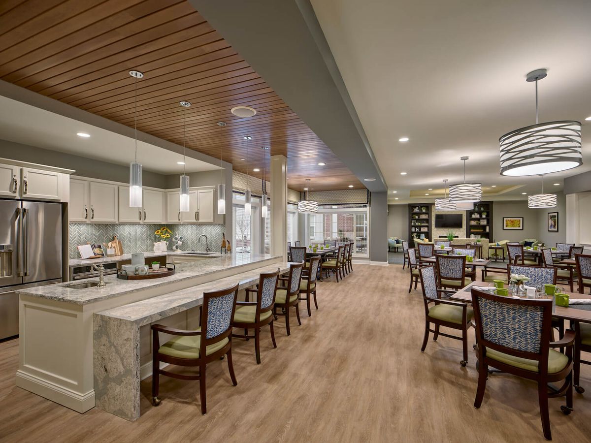 A modern dining area with tables and chairs, featuring wood flooring and a spacious layout.
