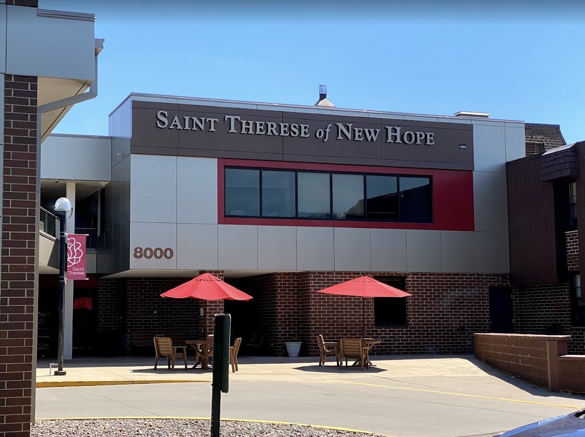 The exterior of Saint Therese of New Hope with outdoor seating and umbrellas.