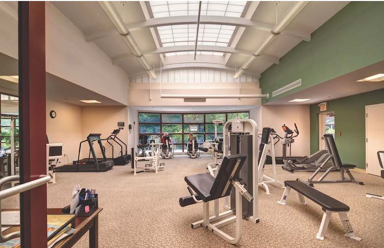 A spacious gym interior with various exercise equipment, including treadmills and weight machines.