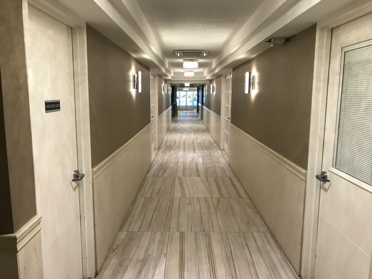 A well-lit hotel hallway with symmetrical design and multiple doors on either side.