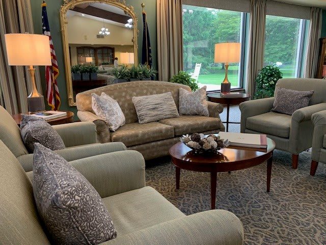 A cozy living room with sofas, armchairs, and a coffee table in front of large windows.