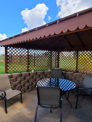 A cozy outdoor gazebo with a table and chairs, surrounded by a lush landscape.