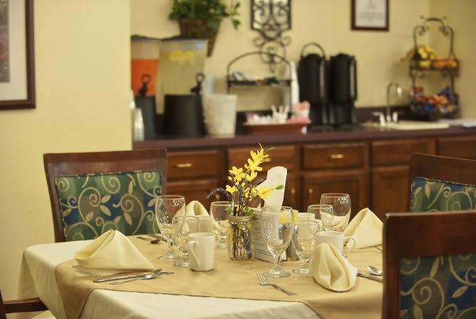 A well-set dining table in a cozy restaurant with napkins, glasses, and floral centerpiece.