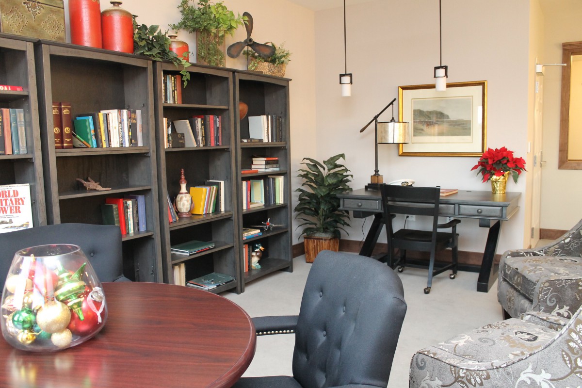A well-organized office space with bookshelves, a desk, and comfortable seating.