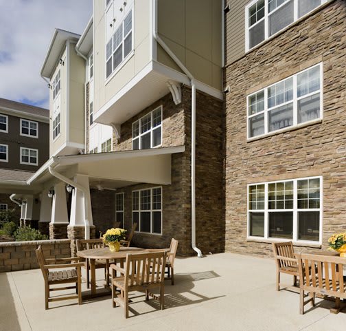 A modern apartment complex with an outdoor patio area furnished with wooden tables and chairs.