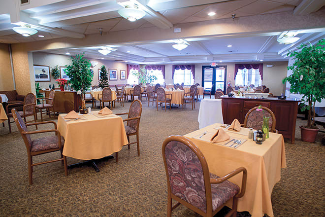 A spacious and elegantly decorated dining area with neatly arranged tables and chairs, featuring warm lighting and a cozy atmosphere.