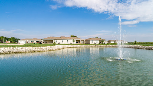 A serene view of waterfront homes nestled along a peaceful lake under a clear blue sky.