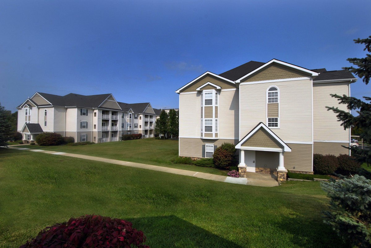 A view of apartment buildings with a well-maintained lawn under a clear blue sky.