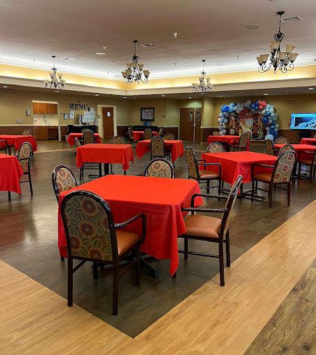 A spacious dining area featuring red tablecloths and decorative chandeliers.