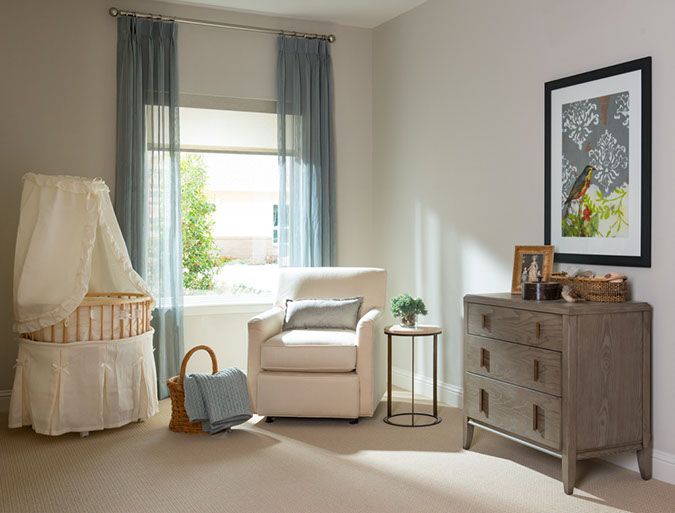 A cozy and well-lit nursery with a crib, armchair, and dresser.