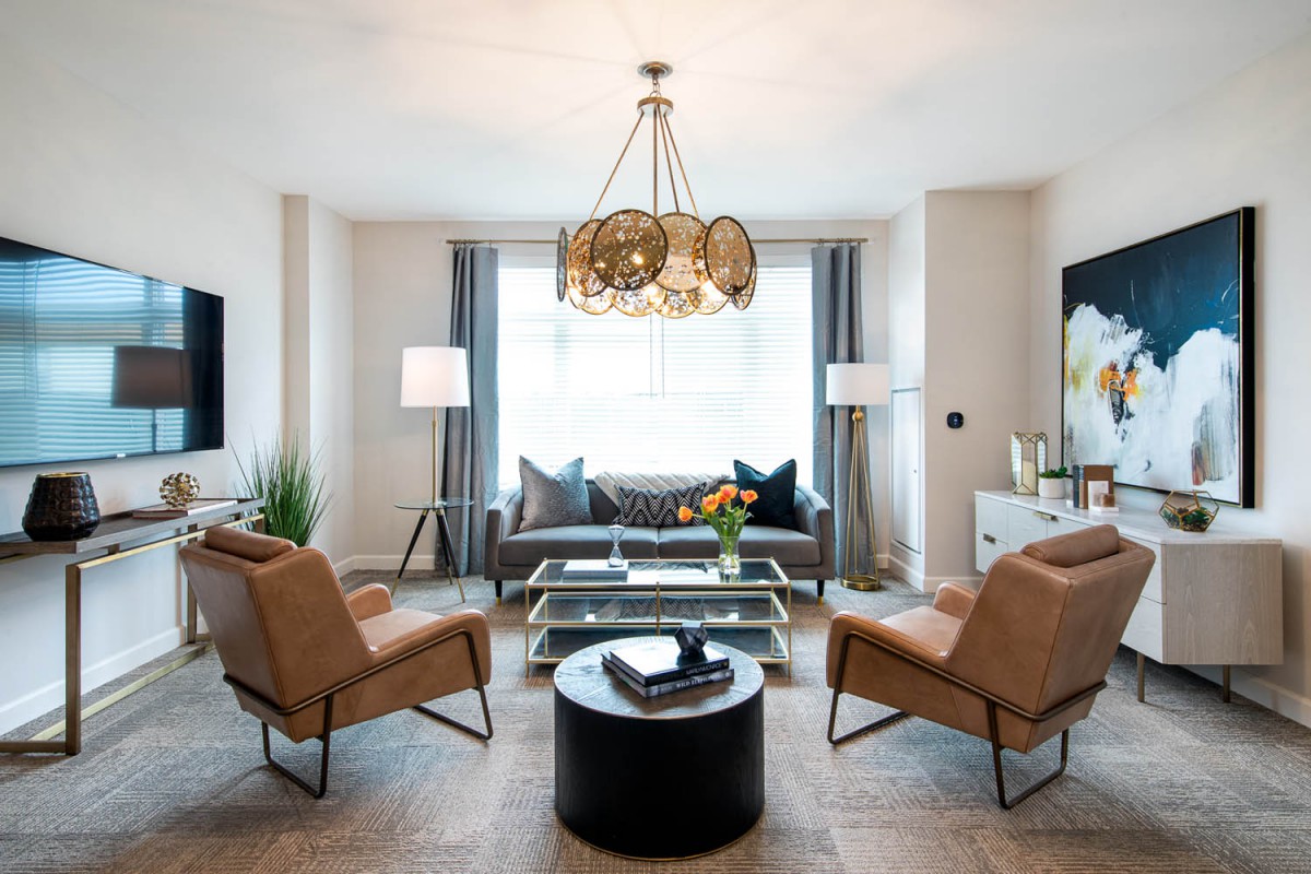 A modern living room featuring a stylish chandelier, comfortable seating, and tasteful decor.