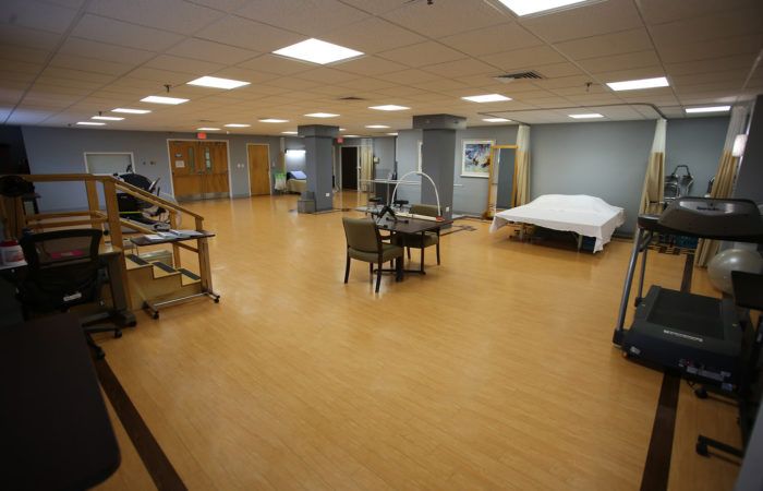 A spacious hospital rehabilitation room with a bed and medical equipment.