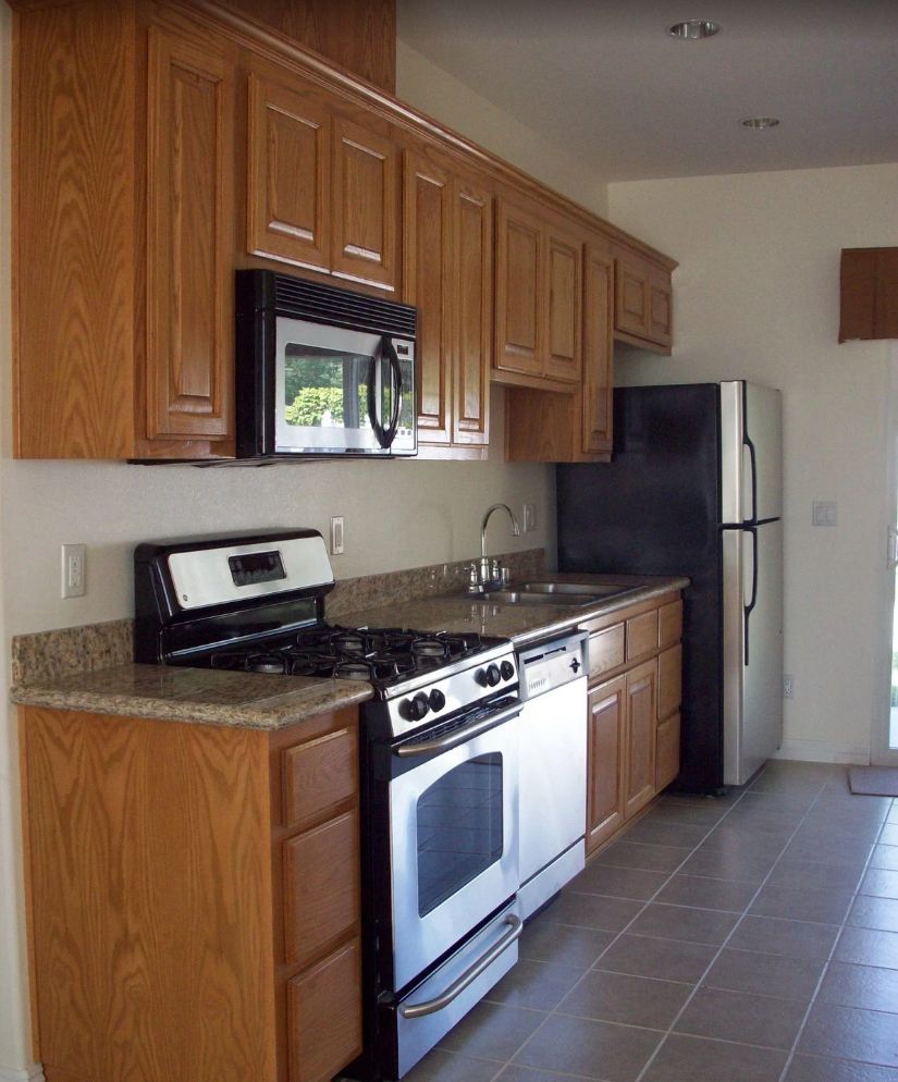 A modern kitchen featuring wooden cabinets, a stove, microwave, and refrigerator.