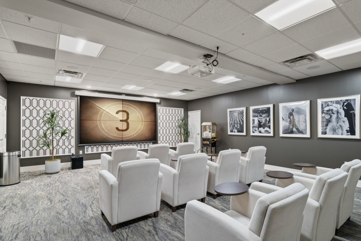 A modern home theater room with white seating and a large projector screen.