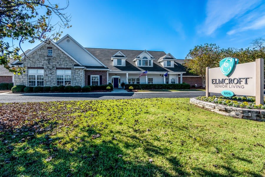 A suburban residential house with a well-maintained lawn and clear blue sky.