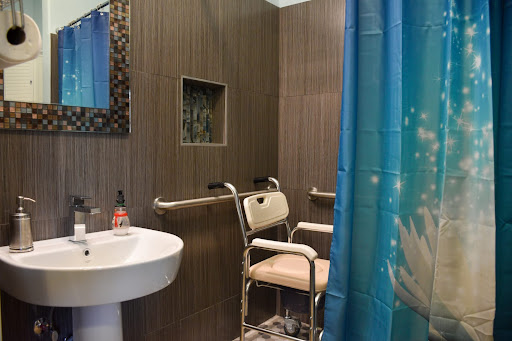 A modern, handicap-accessible bathroom featuring a shower area with safety rails and a sink.