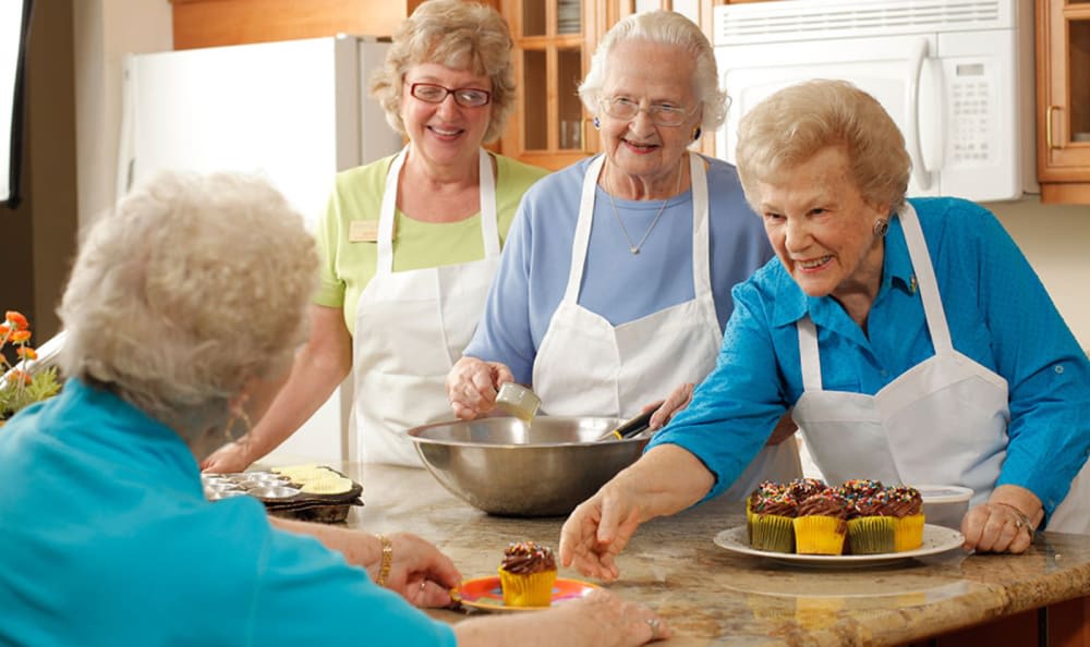 A group of elderly women enjoying a baking session together in the kitchen.