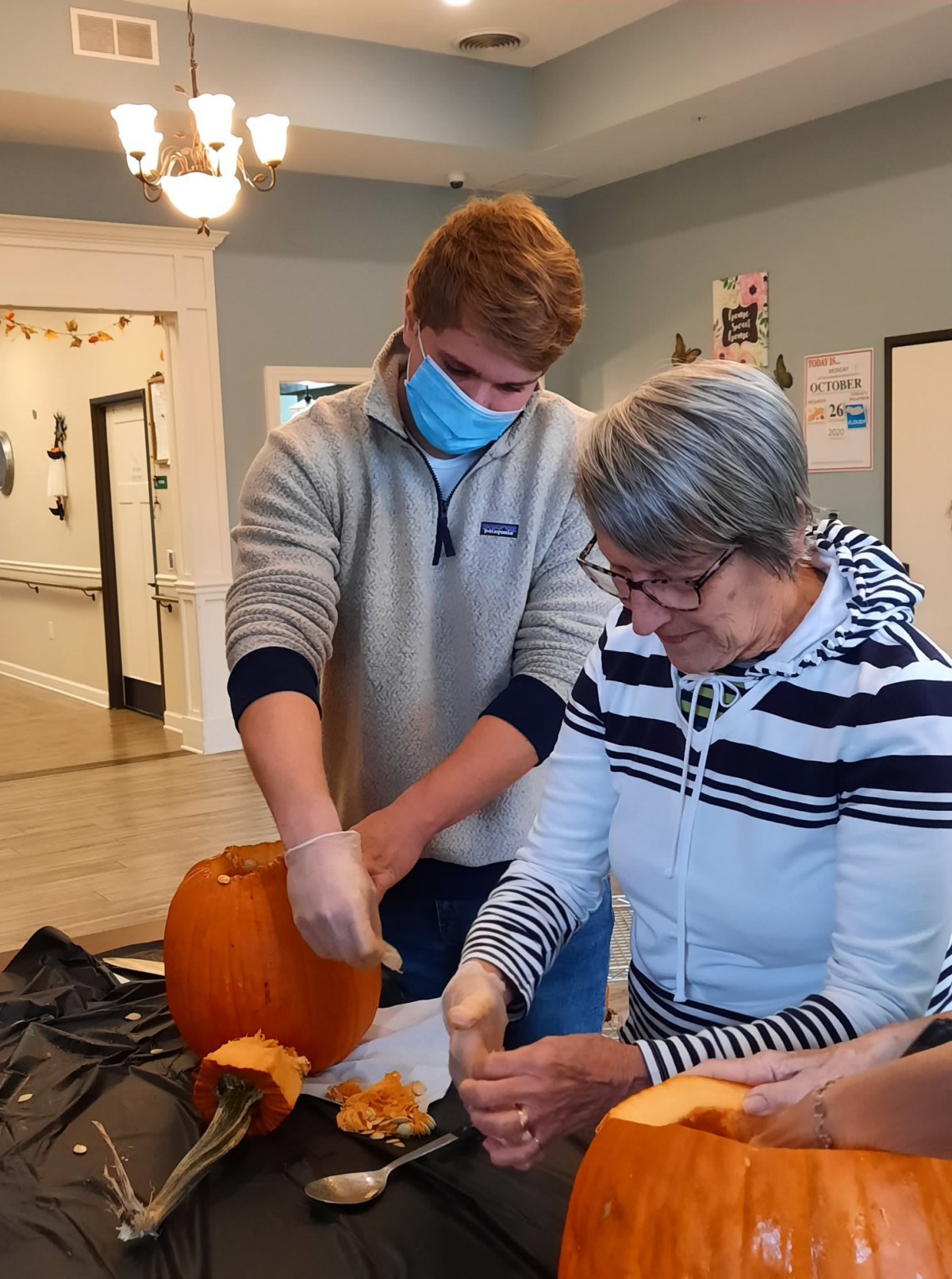 Two people carving a pumpkin indoors while engaging in a fun autumn activity.