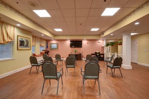 A meeting room with chairs arranged in a circle facing a television on pink walls.